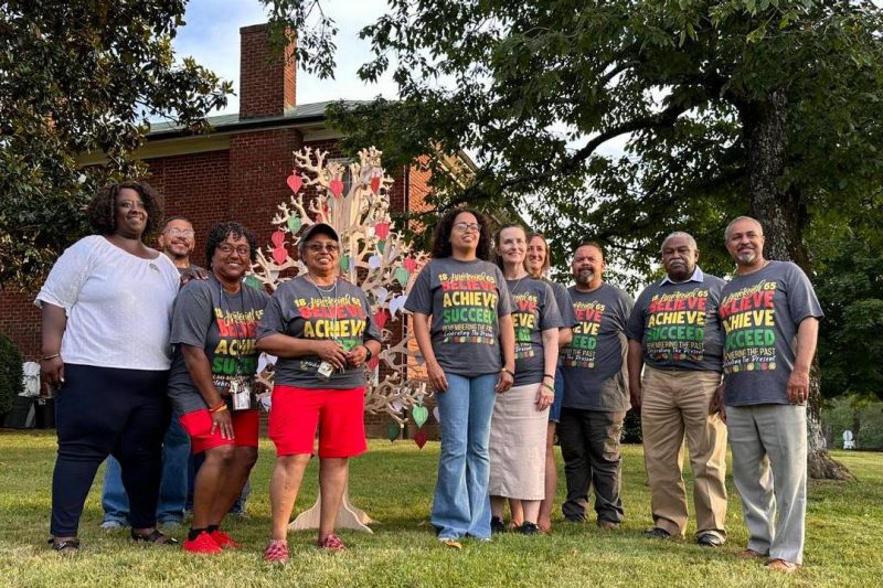 A group of people stand in front of the Reynolds Homestead's historic brick house.