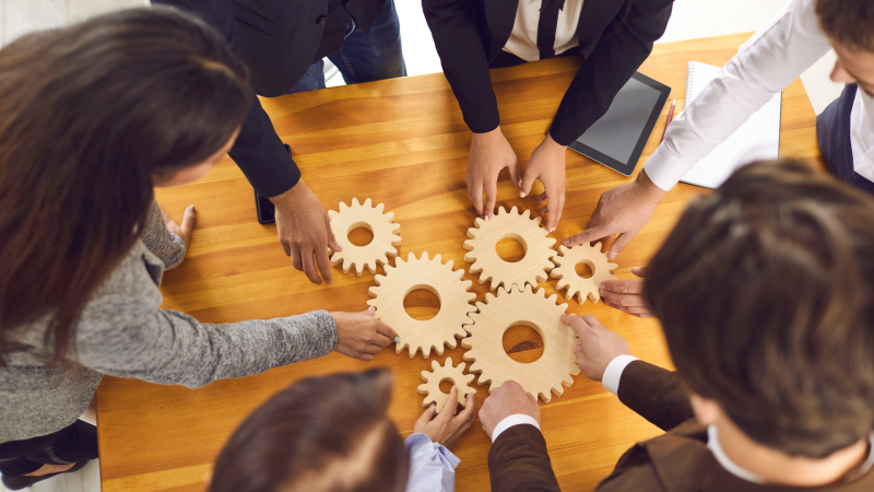 overhead view of people gathered around a table with wooden gears placed on top